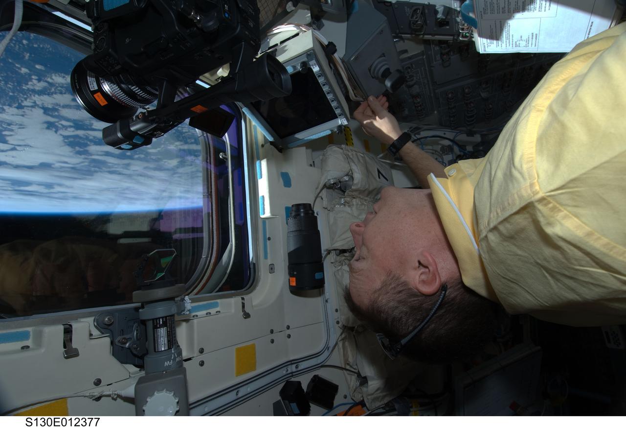 S130-E-012377 (19 Feb. 2010) --- NASA astronaut Terry Virts, STS-130 pilot, looks through an overhead window on the aft flight deck of space shuttle Endeavour during flight day 13 activities.