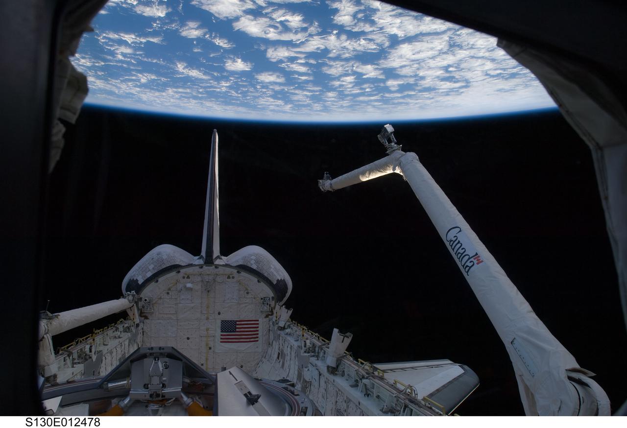 S130-E-012478 (20 Feb. 2010) --- Backdropped by Earth?s horizon and the blackness of space, a partial view of space shuttle Endeavour's payload bay, vertical stabilizer, orbital maneuvering system (OMS) pods, Remote Manipulator System/Orbiter Boom Sensor System (RMS/OBSS) and docking mechanism are featured in this image photographed by an STS-130 crew member from an aft flight deck window.