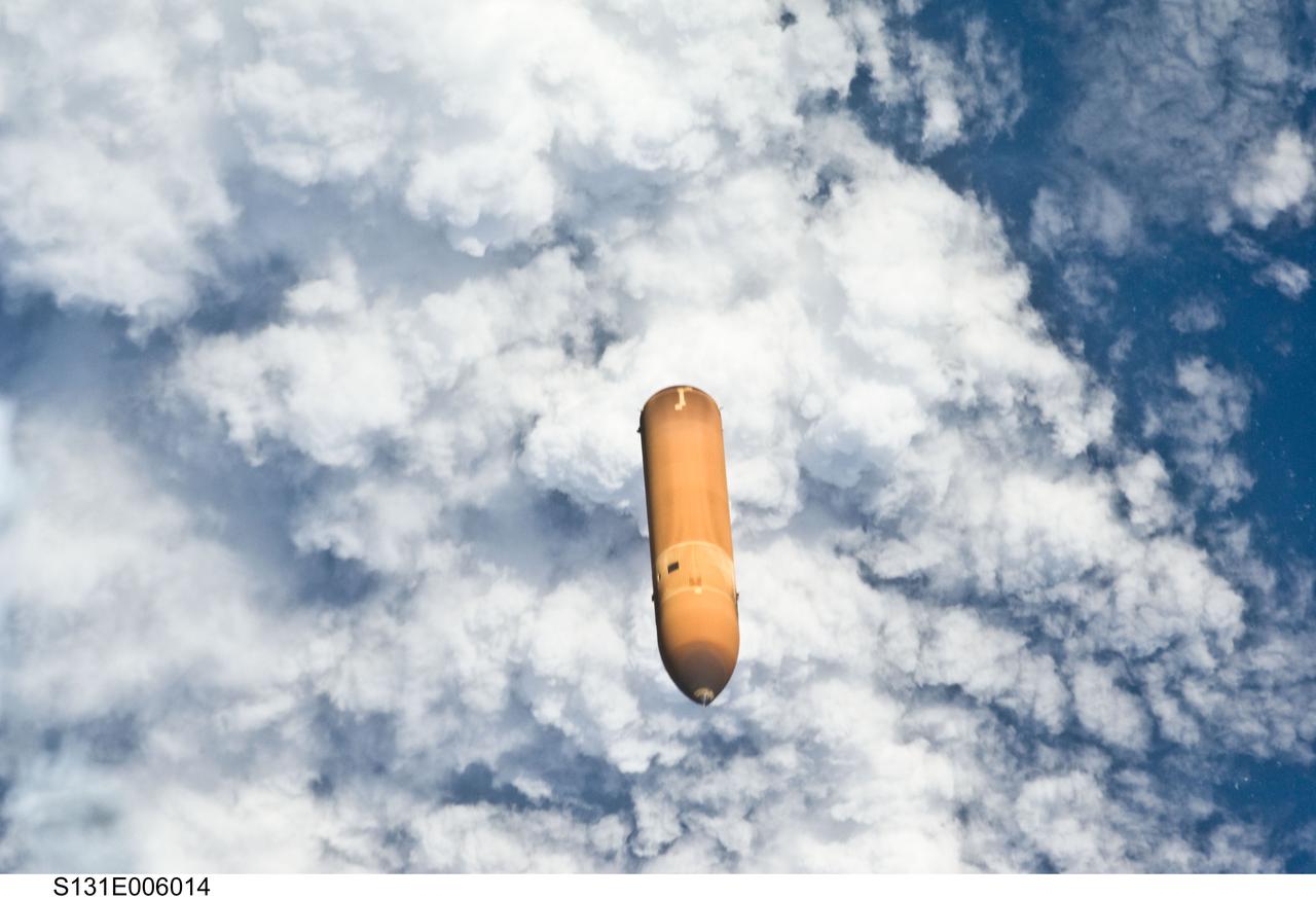 S131-E-006014 (5 April 2010) --- Backdropped by a cloud-covered part of Earth, the STS-131 external fuel tank (ET) begins its relative separation from the Space Shuttle Discovery following launch.