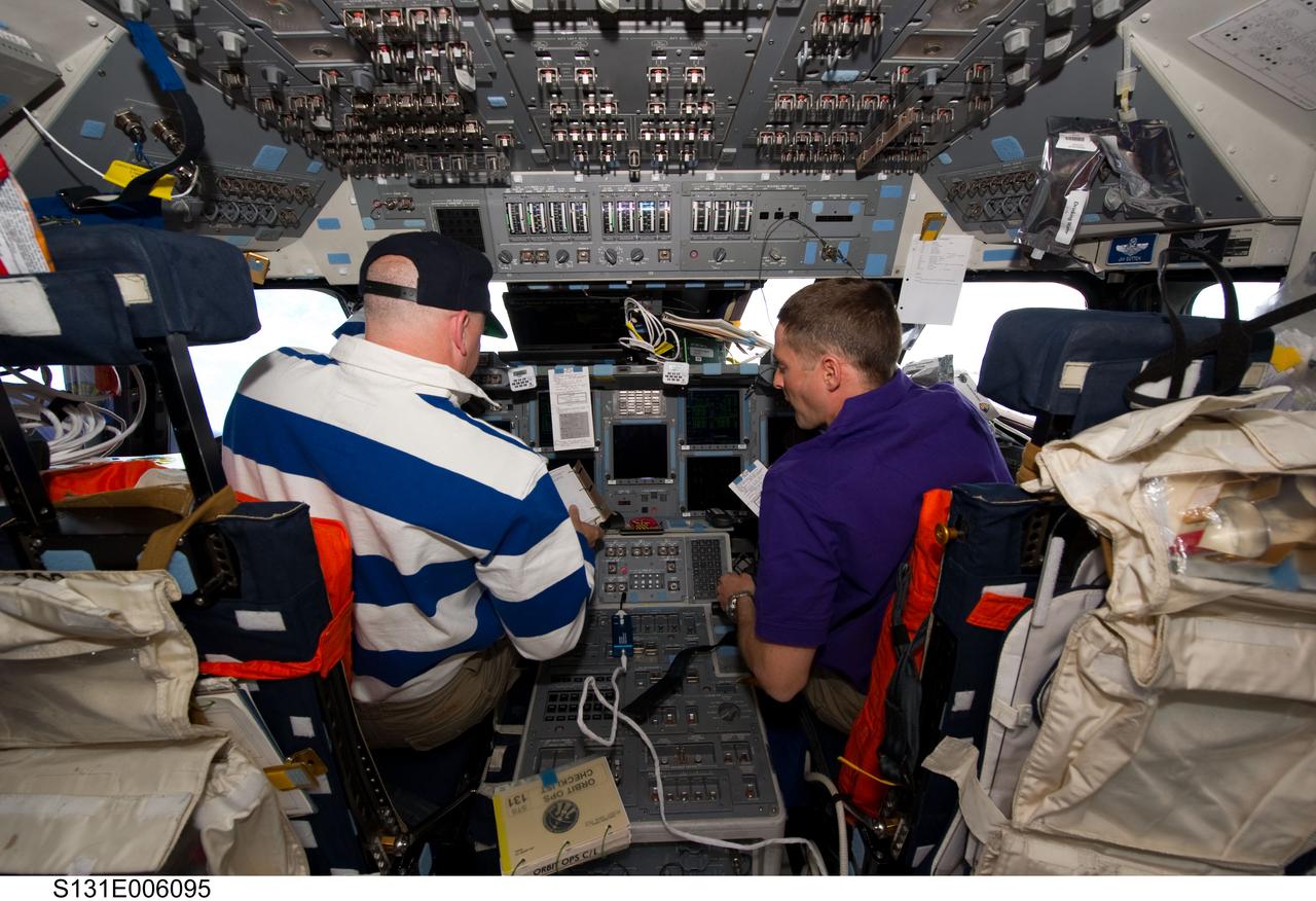 S131-E-006095 (6 April 2010) --- NASA astronauts Alan Poindexter (left), STS-131 commander; and James P. Dutton Jr., pilot, work on the forward flight deck of space shuttle Discovery during flight day two activities.