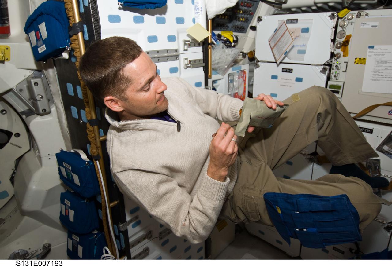 S131-E-007193 (6 April 2010) --- NASA astronaut James P. Dutton Jr., STS-131 pilot, eats snack on the middeck of space shuttle Discovery during flight day two activities.