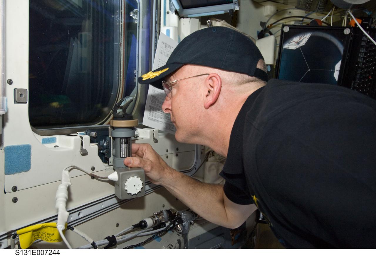 S131-E-007244 (7 April 2010) --- NASA astronaut Alan Poindexter, STS-131 commander, looks through a window on the aft flight deck of space shuttle Discovery during flight day three activities.