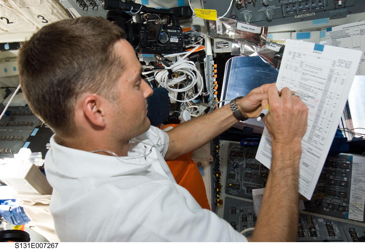 S131-E-007267 (7 April 2010) --- NASA astronaut James P. Dutton Jr., STS-131 pilot, writes notes on a checklist while working on the aft flight deck of space shuttle Discovery during flight day three activities.