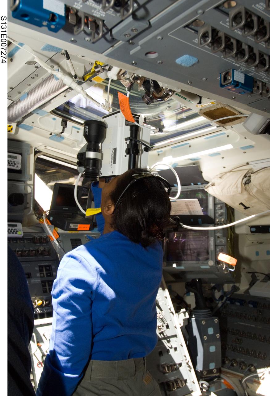 S131-E-007274 (7 April 2010) --- NASA astronaut Stephanie Wilson, STS-131 mission specialist, uses a handheld laser ranging device -- designed to measure the range between two spacecraft -- through one of the overhead windows on the aft flight deck of space shuttle Discovery during flight day three activities.
