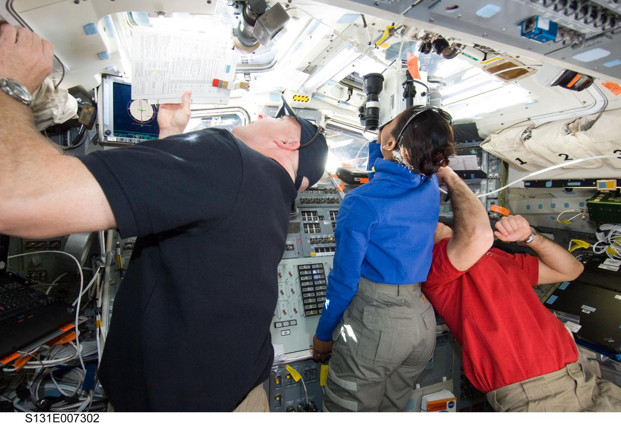 S131-E-007302 (7 April 2010) --- NASA astronauts Alan Poindexter (left), STS-131 commander; Stephanie Wilson and Rick Mastracchio, both mission specialists, look through overhead windows on the aft flight deck of space shuttle Discovery during flight day three activities. Wilson is using a handheld laser ranging device -- designed to measure the range between two spacecraft.