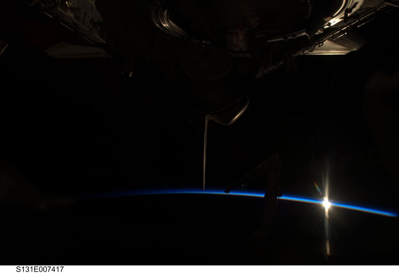 S131-E-007417 (6 April 2010) --- The thin line of Earth's atmosphere, rising sun and space shuttle Discovery are featured in this image photographed by an STS-131 crew member during flight day two activities.
