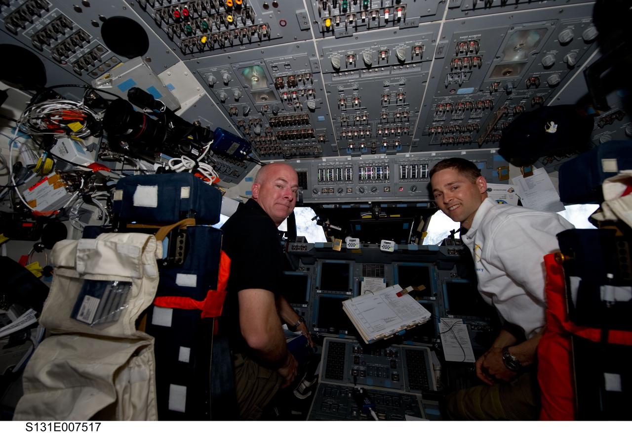 S131-E-007517 (7 April 2010) --- NASA astronauts Alan Poindexter (left) and James P. Dutton Jr., STS-131 commander and pilot, respectively, are pictured at their stations on the forward flight deck of space shuttle Discovery during flight day three activities.