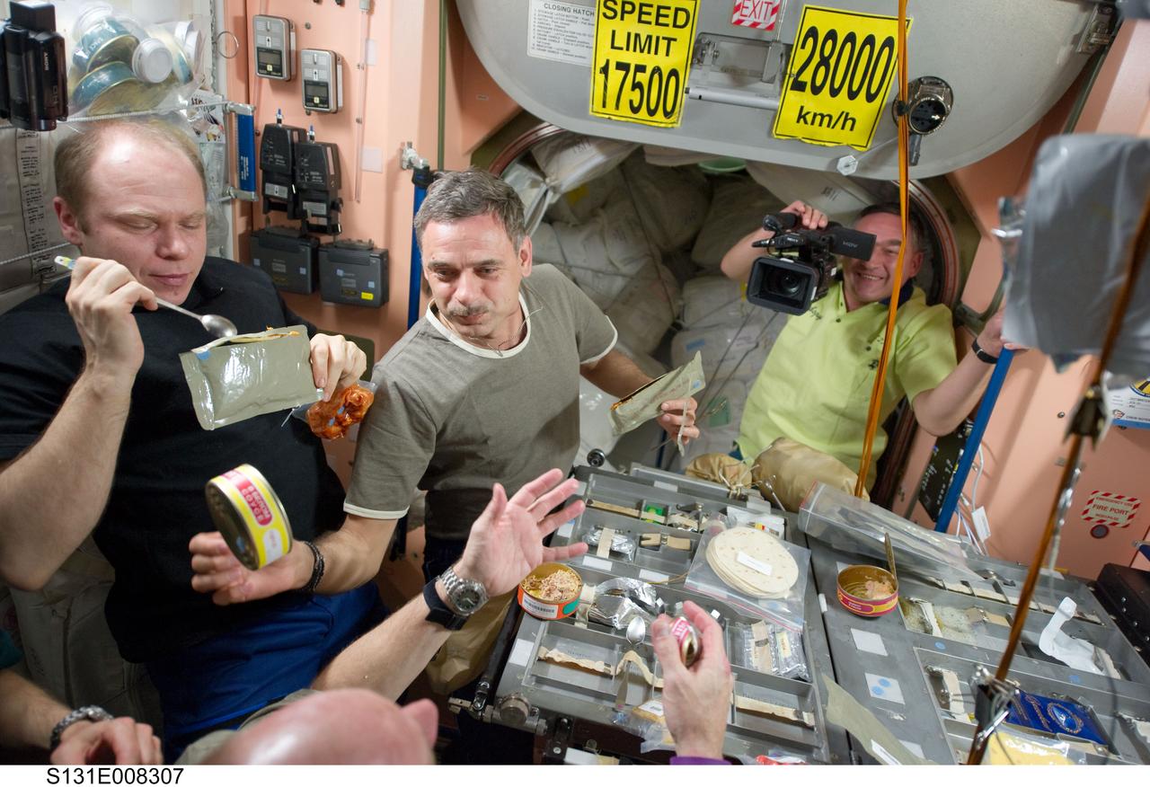 S131-E-008307 (9 April 2010) --- Three Expedition 23 crew members share a meal at the galley in the Unity node of the International Space Station. Pictured from the left are Russian cosmonauts Oleg Kotov, commander; Mikhail Kornienko and Alexander Skvortsov, both flight engineers. Skvortsov had interrupted his meal to document the station crew members and the visiting Discovery astronauts (out of frame) during the meal. Thirteen cosmonauts and astronauts will continue their joint activities over the next several days aboard the orbital complex.