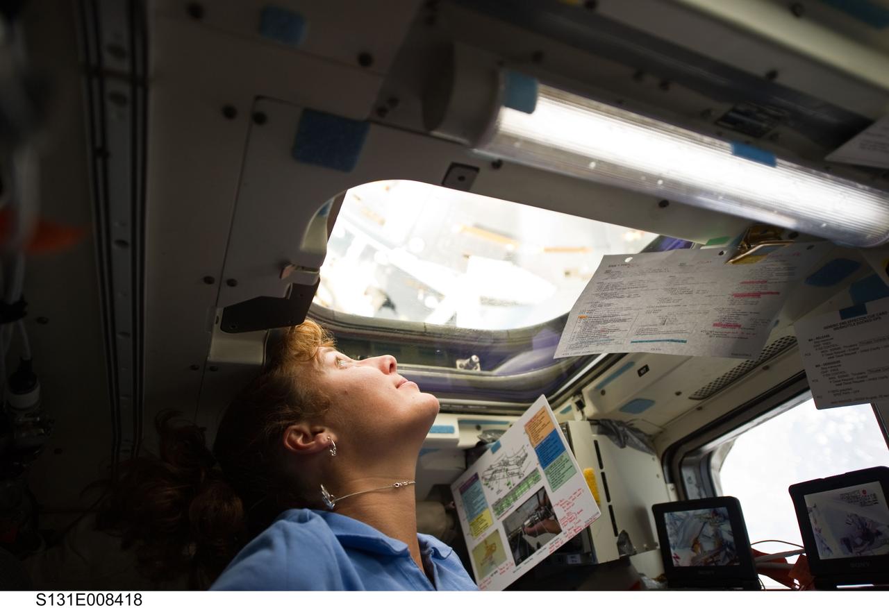 S131-E-008418 (9 April 2010) --- After many months of training in simulators, NASA astronaut Dorothy Metcalf-Lindenburger, STS-131 mission specialist, gets to put her skills to work at the controls for the shuttle Remote Manipulator System on Discovery's aft flight deck during her crew's flight day five activities. Her work is being shared with six Discovery crewmates as well as the six cosmonauts and astronauts currently assigned to the International Space Station.