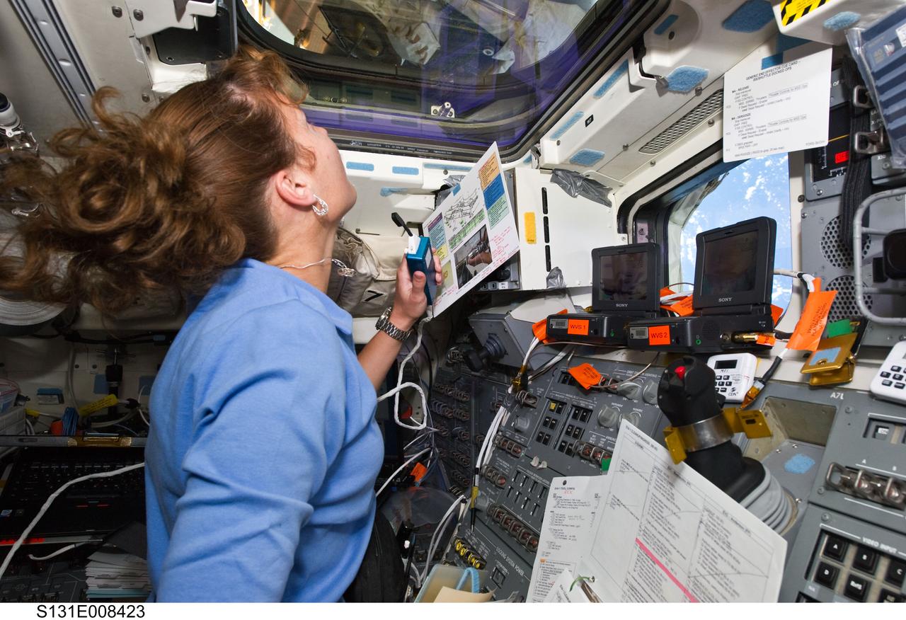 S131-E-008423 (9 April 2010) --- After many months of training in simulators, NASA astronaut Dorothy Metcalf-Lindenburger, STS-131 mission specialist, gets to put her skills to work at the controls for the shuttle Remote Manipulator System on Discovery's aft flight deck during her crew's flight day five activities. Her work is being shared with six Discovery crewmates as well as the six cosmonauts and astronauts currently assigned to the International Space Station.