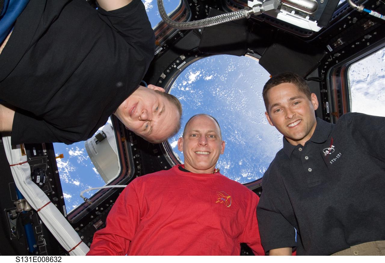 S131-E-008632 (10 April 2010) --- Russian cosmonaut Oleg Kotov (left), Expedition 23 commander; along with NASA astronauts Clayton Anderson (center), STS-131 mission specialist; and James P. Dutton Jr., STS-131 pilot, pose for a photo near the windows in the Cupola of the International Space Station while space shuttle Discovery remains docked with the station.