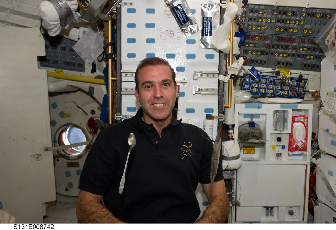 S131-E-008742 (11 April 2010) --- NASA astronaut Rick Mastracchio, STS-131 mission specialist, is pictured near a spoon and food package floating freely on the middeck of space shuttle Discovery while docked with the International Space Station.