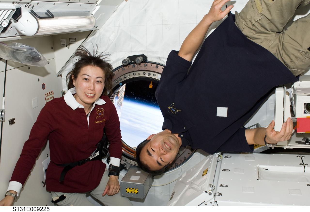 S131-E-009225 (12 April 2010) --- Japan Aerospace Exploration Agency (JAXA) astronauts Naoko Yamazaki (left), STS-131 mission specialist; and Soichi Noguchi, Expedition 23 flight engineer, pose for a photo near a window in the Kibo laboratory of the International Space Station while space shuttle Discovery remains docked with the station.