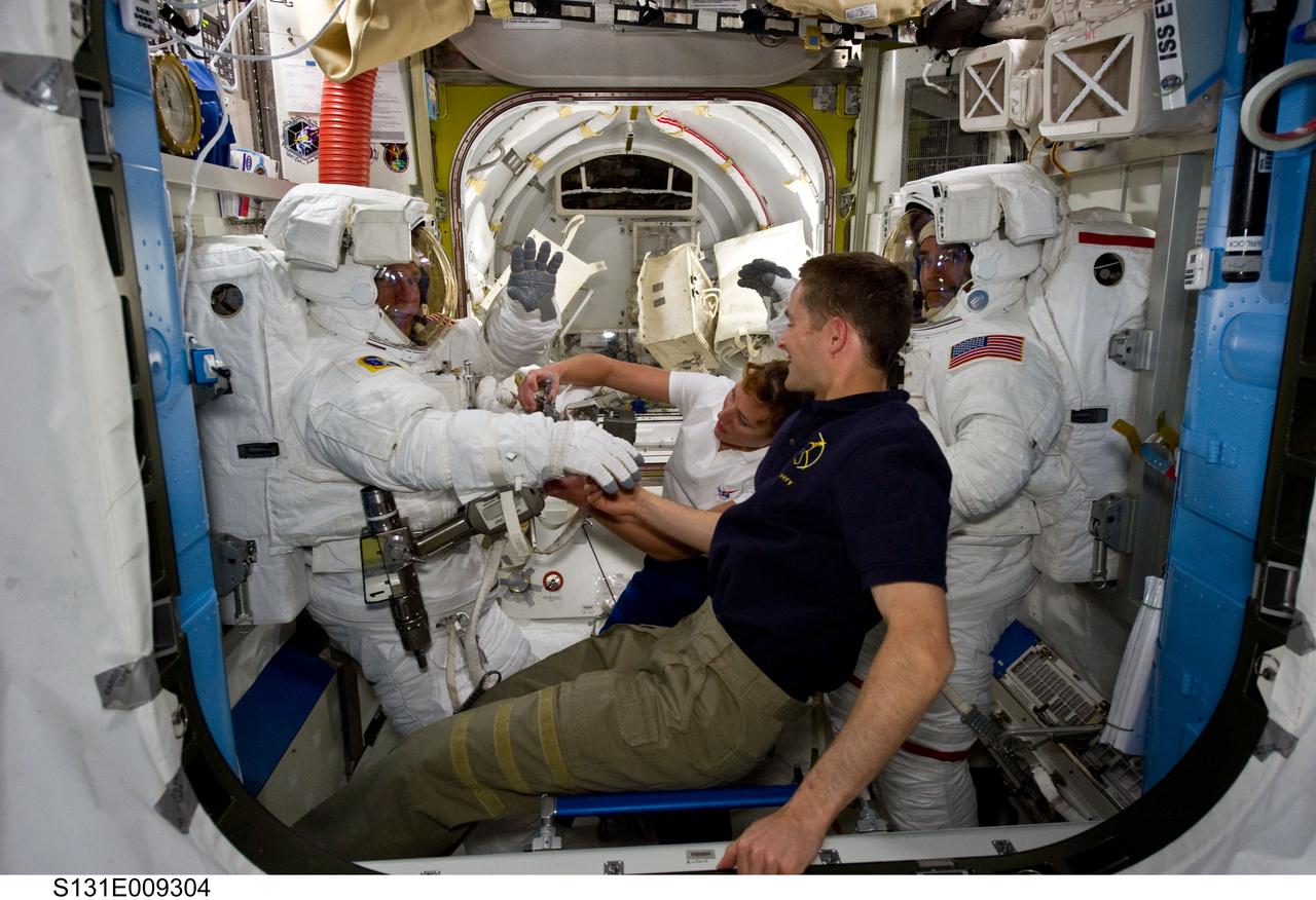 S131-E-009304 (13 April 2010) --- NASA astronauts Clayton Anderson (left) and Rick Mastracchio, both STS-131 mission specialists, attired in their Extravehicular Mobility Unit (EMU) spacesuits; along with astronauts James P. Dutton Jr., pilot; and Dorothy Metcalf-Lindenburger, mission specialist, are pictured in the Quest airlock of the International Space Station prior to the start of the mission's third and final spacewalk.