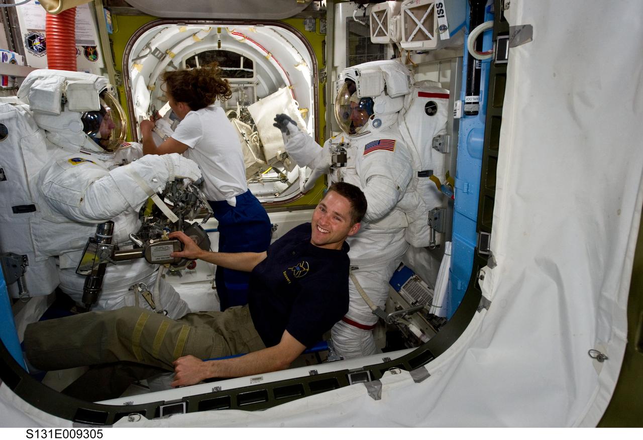 S131-E-009305 (13 April 2010) --- NASA astronauts Clayton Anderson (left) and Rick Mastracchio, both STS-131 mission specialists, attired in their Extravehicular Mobility Unit (EMU) spacesuits; along with astronauts James P. Dutton Jr., pilot; and Dorothy Metcalf-Lindenburger, mission specialist, are pictured in the Quest airlock of the International Space Station prior to the start of the mission's third and final spacewalk.