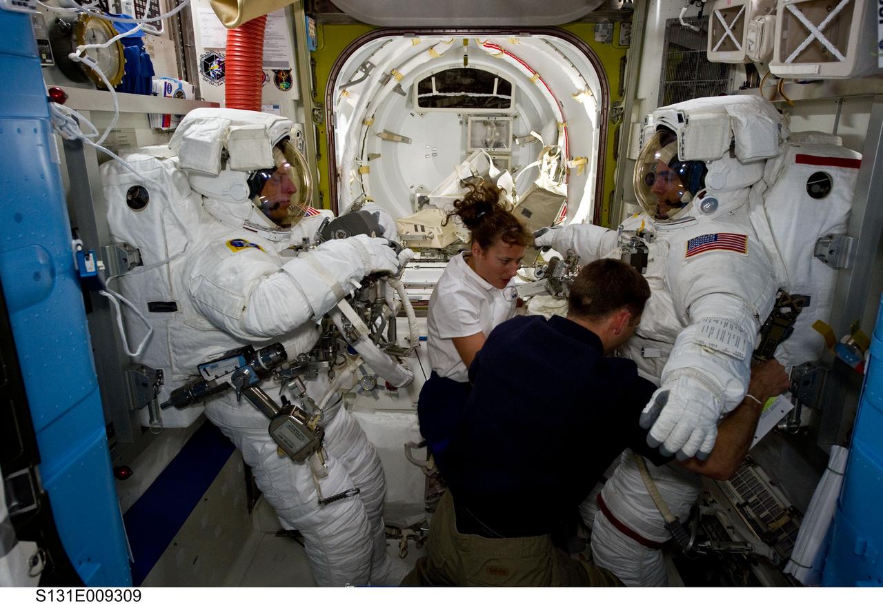 S131-E-009309 (13 April 2010) --- NASA astronauts Clayton Anderson (left) and Rick Mastracchio, both STS-131 mission specialists, attired in their Extravehicular Mobility Unit (EMU) spacesuits; along with astronauts James P. Dutton Jr., pilot; and Dorothy Metcalf-Lindenburger, mission specialist, are pictured in the Quest airlock of the International Space Station prior to the start of the mission's third and final spacewalk.
