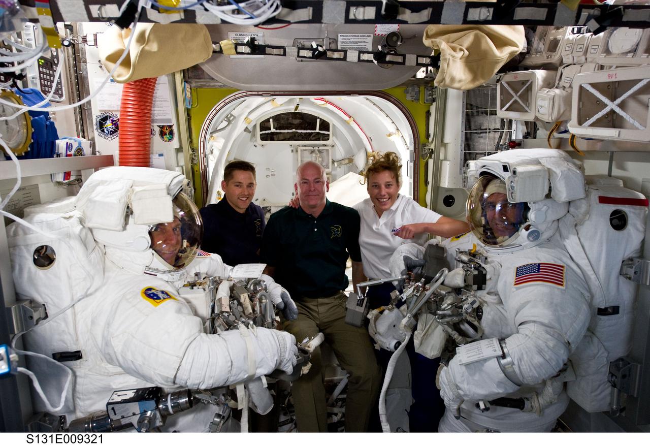 S131-E-009321 (13 April 2010) --- NASA astronauts Clayton Anderson (left) and Rick Mastracchio, both STS-131 mission specialists, attired in their Extravehicular Mobility Unit (EMU) spacesuits; along with astronauts Alan Poindexter (center background), commander; James P. Dutton Jr., pilot; and Dorothy Metcalf-Lindenburger, mission specialist, pose for a photo in the Quest airlock of the International Space Station prior to the start of the mission's third and final spacewalk.