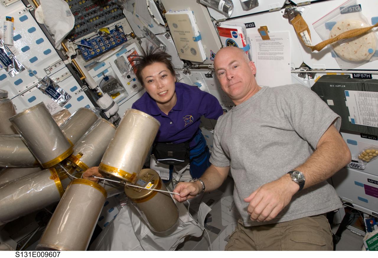 S131-E-009607 (13 April 2010) --- NASA astronaut Alan Poindexter, STS-131 commander; and Japan Aerospace Exploration Agency (JAXA) astronaut Naoko Yamazaki, mission specialist, work with lithium hydroxide (LiOH) canisters on space shuttle Discovery’s middeck while docked with the International Space Station.