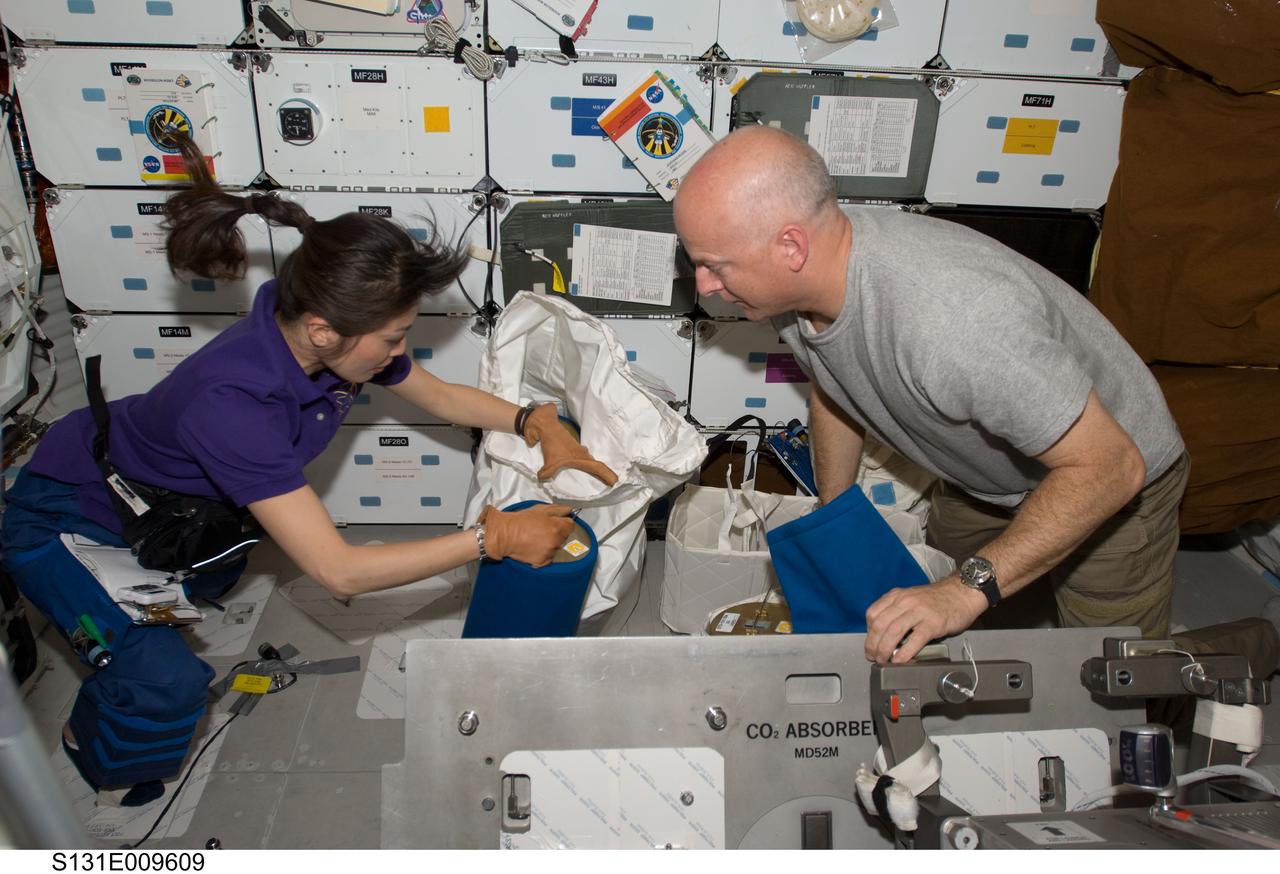S131-E-009609 (13 April 2010) --- NASA astronaut Alan Poindexter, STS-131 commander; and Japan Aerospace Exploration Agency (JAXA) astronaut Naoko Yamazaki, mission specialist, work with lithium hydroxide (LiOH) canisters on space shuttle Discovery’s middeck while docked with the International Space Station.