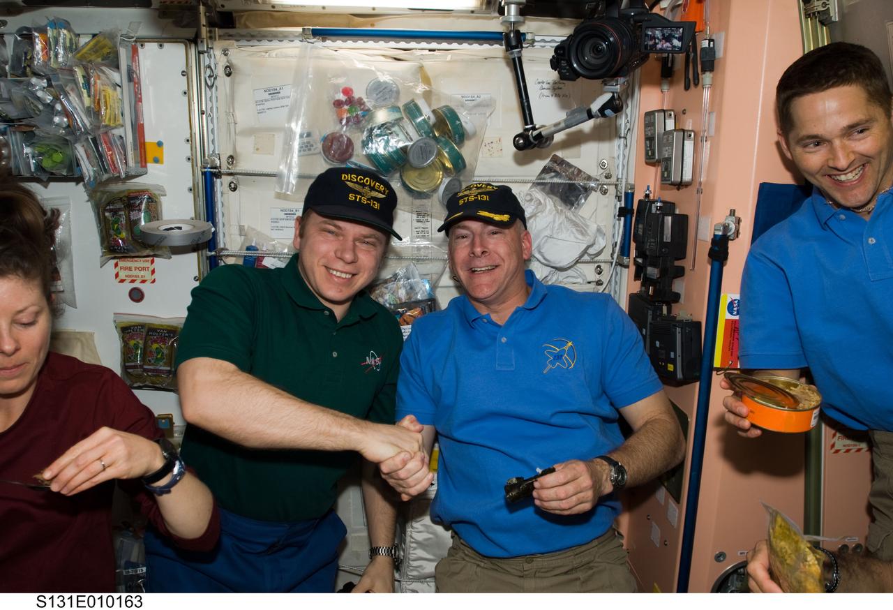 S131-E-010163 (14 April 2010) --- Russian cosmonaut Oleg Kotov (left), Expedition 23 commander; and NASA astronaut Alan Poindexter, STS-131 commander, shake hands in the Unity node of the International Space Station while space shuttle Discovery remains docked with the station. NASA astronauts James P. Dutton Jr., STS-131 pilot; and Tracy Caldwell Dyson, Expedition 23 flight engineer, are also pictured.