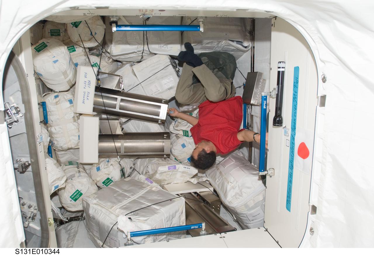 S131-E-010344 (16 April 2010) --- Japan Aerospace Exploration Agency (JAXA) astronaut Soichi Noguchi, Expedition 23 flight engineer, works among stowage containers in the Japanese Logistics Module - Pressurized Section (JLP) of the International Space Station while space shuttle Discovery (STS-131) remains docked with the station.