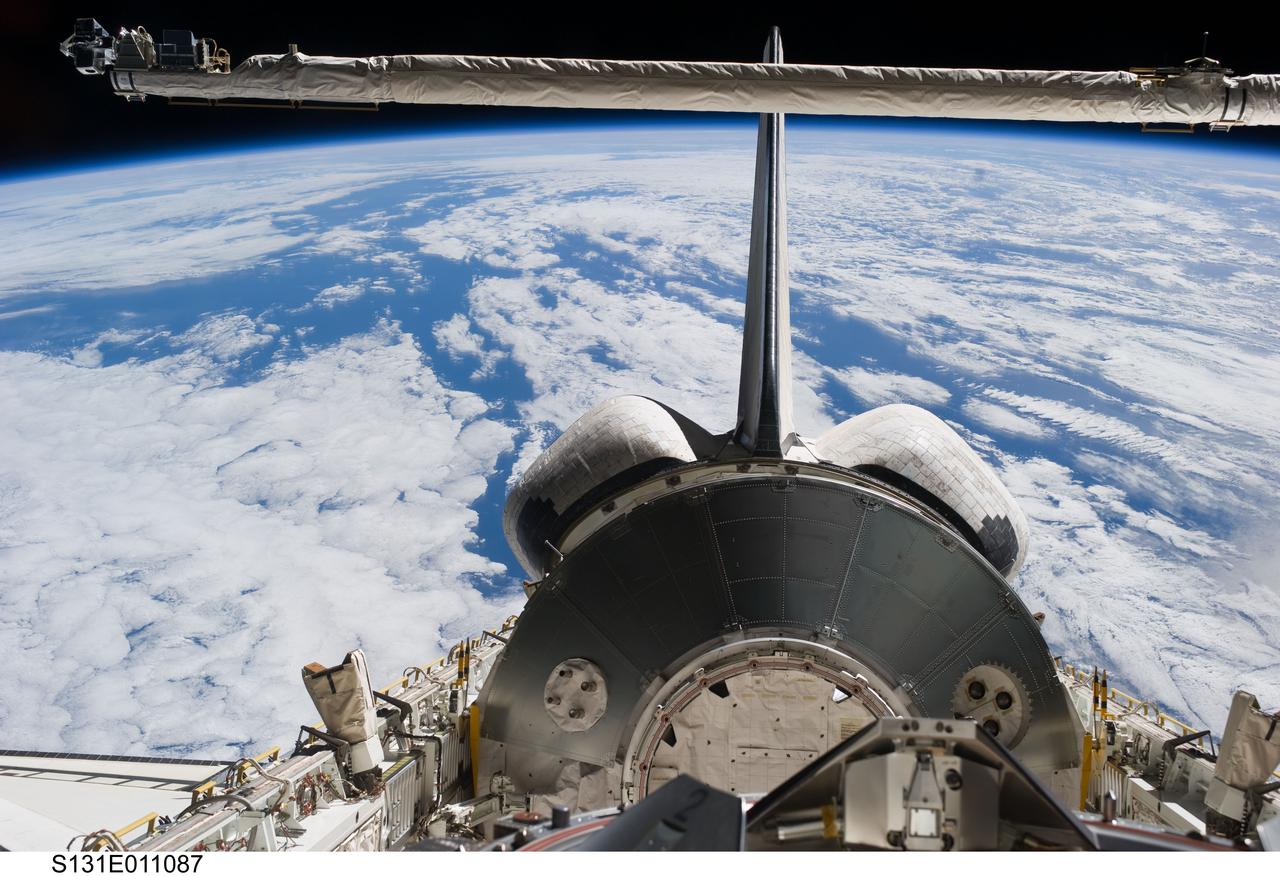 S131-E-011087 (17 April 2010) --- The Leonardo Multi-Purpose Logistics Module (MPLM) visible in space shuttle Discovery's payload bay, docking mechanism, vertical stabilizer, orbital maneuvering system (OMS) pods and Remote Manipulator System/Orbiter Boom Sensor System (RMS/OBSS) are featured in this image photographed by an STS-131 crew member from an aft flight deck window. A blue and white part of Earth provides the backdrop for the scene.