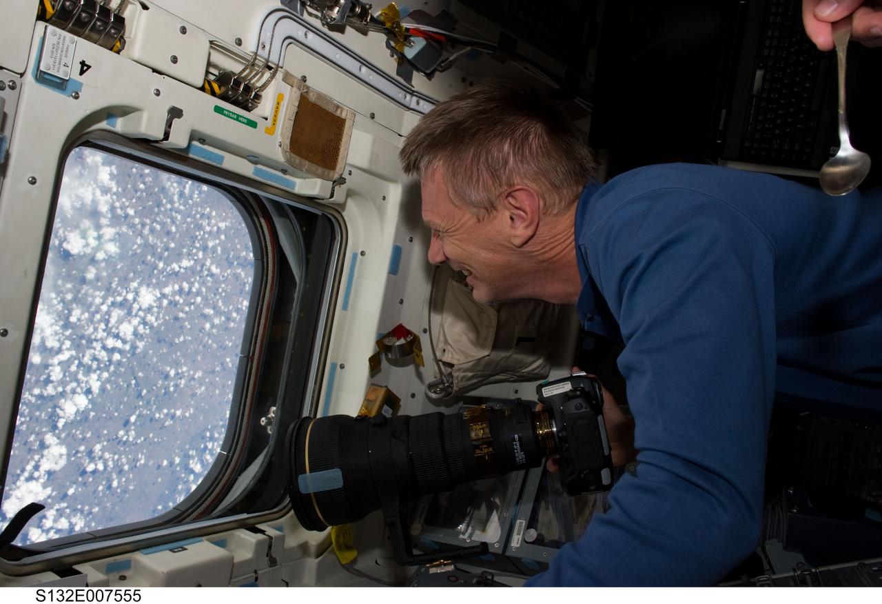 S132-E-007555 (15 May 2010) --- NASA astronaut Piers Sellers, STS-132 mission specialist, holds a still camera while looking through an overhead window on the aft flight deck of the Earth-orbiting space shuttle Atlantis during flight day two activities.