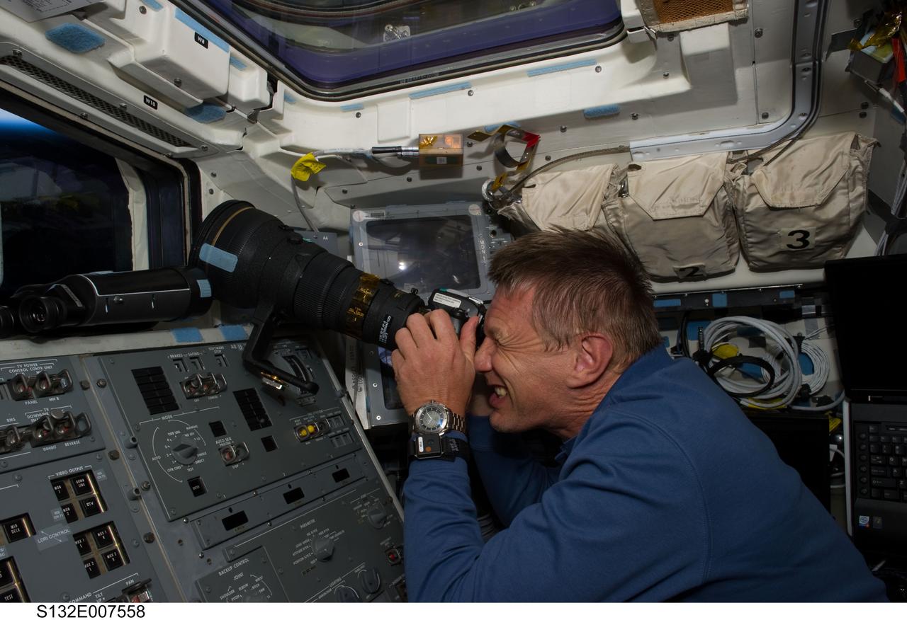 S132-E-007558 (15 May 2010) --- NASA astronaut Piers Sellers, STS-132 mission specialist, uses a still camera at a window on the aft flight deck of the Earth-orbiting space shuttle Atlantis during flight day two activities.