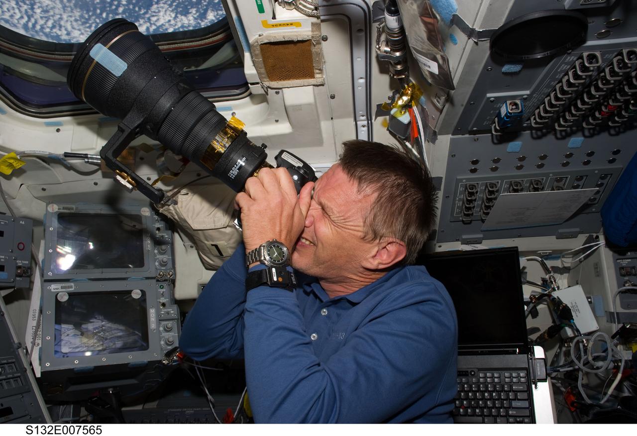 S132-E-007565 (15 May 2010) --- NASA astronaut Piers Sellers, STS-132 mission specialist, uses a still camera at an overhead window on the aft flight deck of the Earth-orbiting space shuttle Atlantis during flight day two activities.