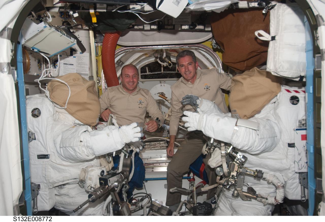 S132-E-008772 (20 May 2010) --- NASA astronauts Garrett Reisman (left) and Michael Good, both STS-132 mission specialists, pose for a photo between two Extravehicular Mobility Unit (EMU) spacesuits in the Quest airlock of the International Space Station while space shuttle Atlantis remains docked with the station.