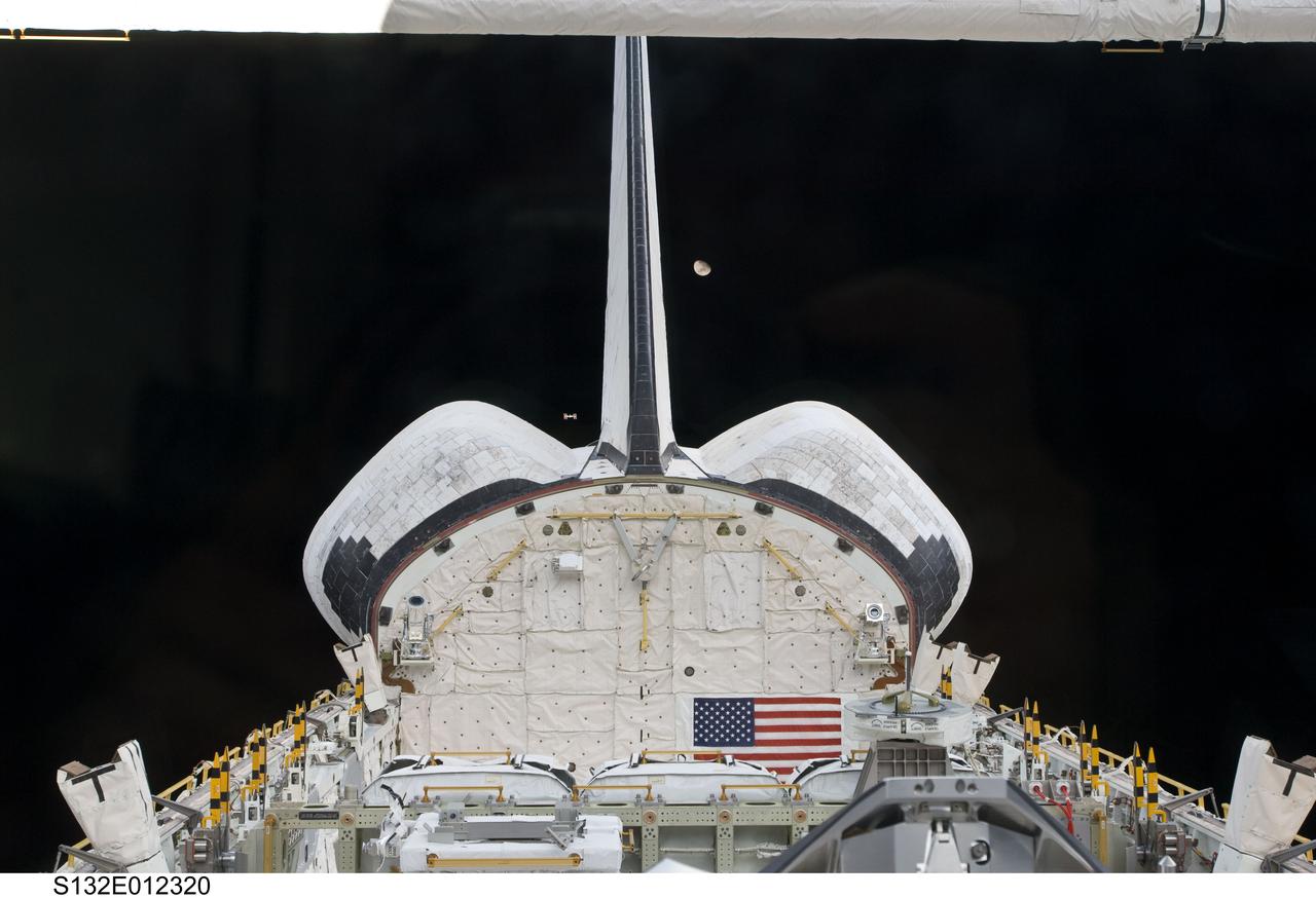 S132-E-012320 (23 May 2010) --- Space shuttle Atlantis? vertical stabilizer, orbital maneuvering system (OMS) pods and payload bay; along with the distant International Space Station and moon are featured in this image photographed by an STS-132 crew member onboard the shuttle. The space station appears very small from the point of view of the Atlantis as the two spacecraft carry out their relative separation. Undocking of the two spacecraft occurred at 10:22 a.m. (CDT) on May 23, 2010.