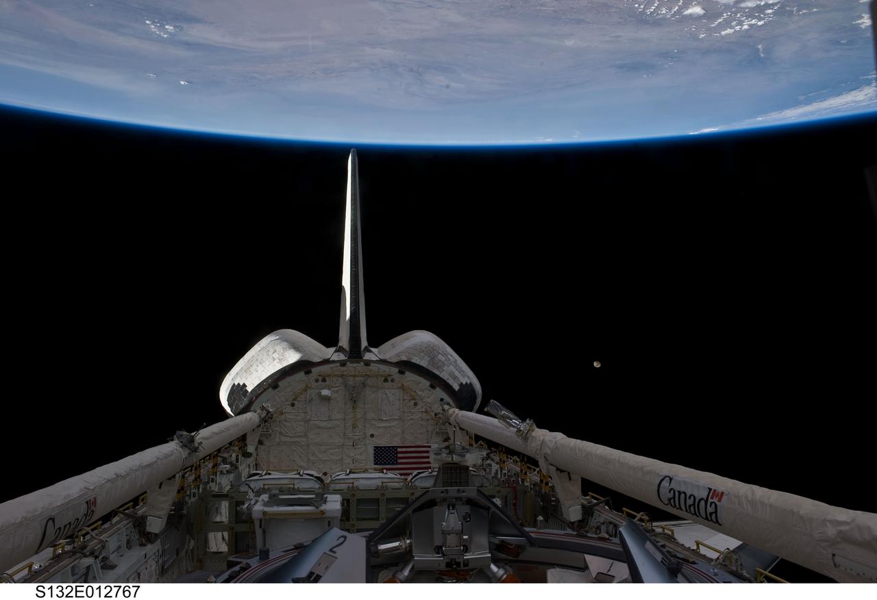 S132-E-012767 (25 May 2010) --- Space shuttle Atlantis’ vertical stabilizer, orbital maneuvering system (OMS) pods, remote manipulator system/orbiter boom sensor system (RMS/OBSS), payload bay and docking mechanism are featured in this image photographed by an STS-132 crew member on the shuttle during flight day 12 activities. The moon is visible at center right. Earth’s horizon and the blackness of space provide the backdrop for the scene.