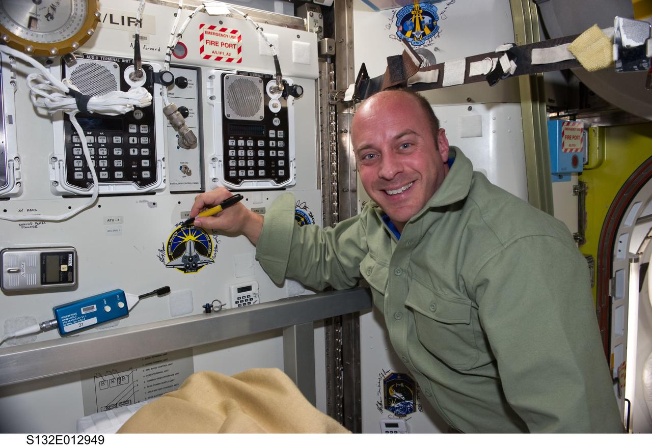 S132-E-012949 (22 May 2010) --- NASA astronaut Garrett Reisman, STS-132 mission specialist, poses for a photo while signing the STS-132 patch, which was added to the growing collection of insignias representing crews who performed spacewalks from the Quest airlock of the International Space Station.