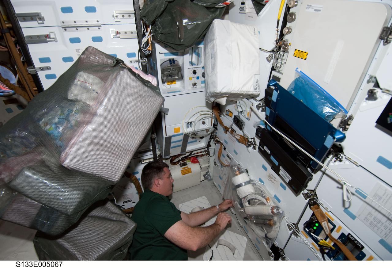 S133-E-005067 (25 Feb. 2011) --- Astronaut Steve Bowen, STS-133 mission specialist, is seen at work on the middeck of the space shuttle Discovery on flight day two. Photo credit: NASA or National Aeronautics and Space Administration