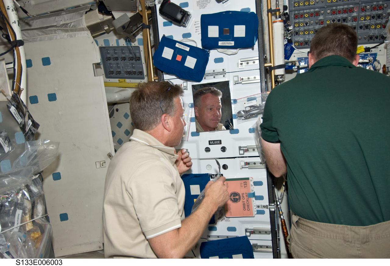 S133-E-006003 (25 Feb. 2011) --- Astronauts Steve Lindsey (left), STS-133 commander, and Steve Bowen, mission specialist, take a break from flight day 2 duties on Discovery's middeck. Lindsey is preparing a snack, as the shuttle makes its way toward a weekend docking with the International Space Station. Photo credit: NASA or National Aeronautics and Space Administration