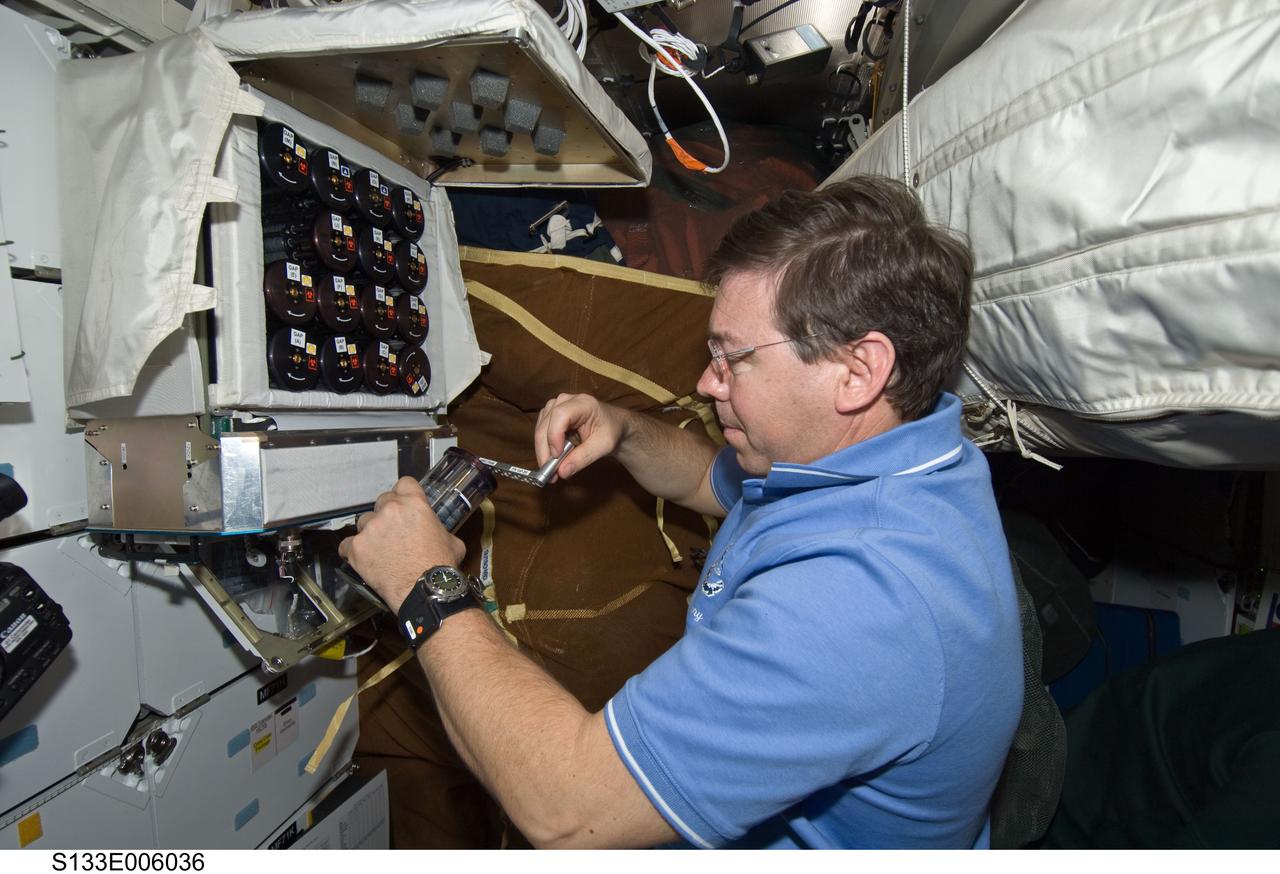 S133-E-006036 (25 Feb. 2011) --- Astronaut Michael Barratt, STS-133 mission specialist, works with the Microbe Group Activation Pack containing eight Fluid Processing Apparatuses on the middeck of space shuttle Discovery while en route to a rendezvous with the International Space Station. A previous set of similar tests made a key discovery about the mechanism that makes salmonella more infectious, aiding the fight against food poisoning on Earth. Photo credit: NASA or National Aeronautics and Space Administration