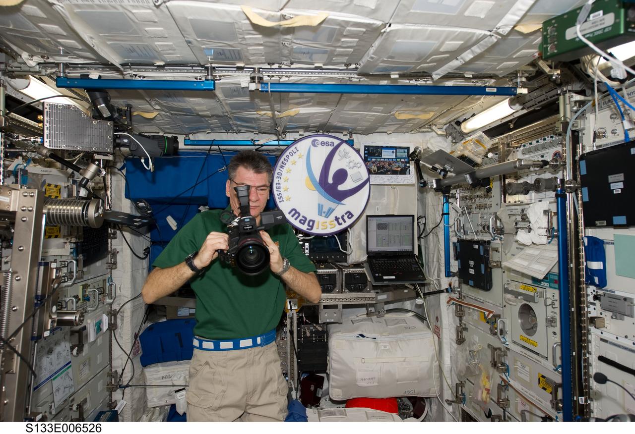 S133-E-006526 (26 Feb. 2011) --- European Space Agency astronaut Paolo Nespoli, Expedition 26 flight engineer, uses a High Definition Video (HDV) camera in the Columbus laboratory of the International Space Station while space shuttle Discovery (STS-133) remains docked with the station. Photo credit: NASA or National Aeronautics and Space Administration