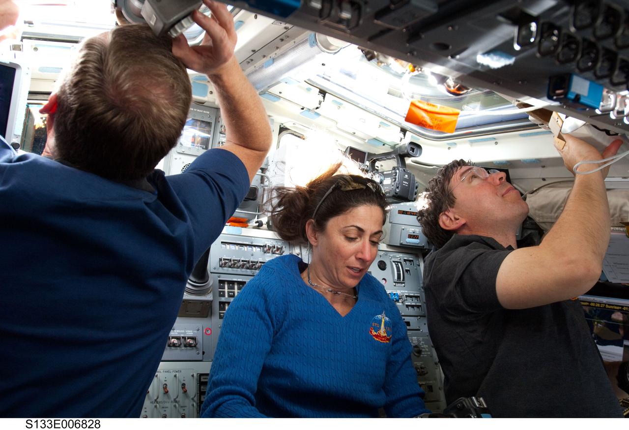 S133-E-006828 (26 Feb. 2011) --- NASA astronauts Steve Lindsey (left), STS-133 commander; Nicole Stott and Michael Barratt, both mission specialists, are busy on the aft flight deck of space shuttle Discovery during flight day three activities. Photo credit: NASA or National Aeronautics and Space Administration