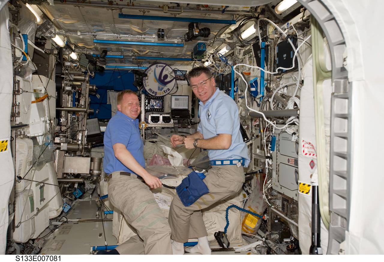 S133-E-007081 (27 Feb. 2011) --- NASA astronaut Eric Boe (left), STS-133 pilot; and European Space Agency astronaut Paolo Nespoli, Expedition 26 flight engineer, work in the Columbus laboratory of the International Space Station while space shuttle Discovery remains docked with the station. Photo credit: NASA or National Aeronautics and Space Administration