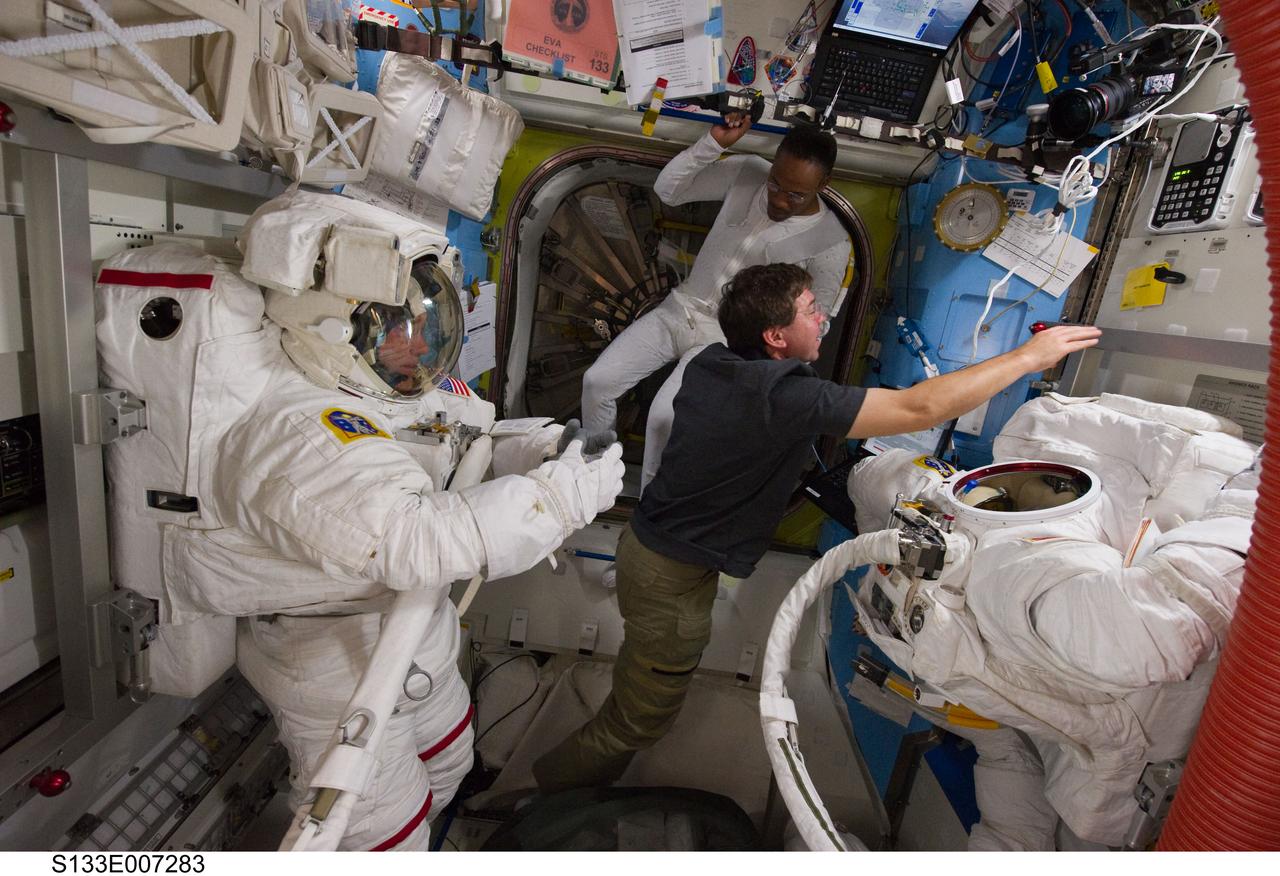 S133-E-007283 (28 Feb. 2011) --- NASA astronauts Steve Bowen (left), Michael Barratt and Alvin Drew (background), all STS-133 mission specialists, are pictured in the Quest airlock of the International Space Station as they prepare for the start of the mission's first spacewalk. Bowen is wearing an Extravehicular Mobility Unit (EMU) spacesuit. Photo credit: NASA or National Aeronautics and Space Administration