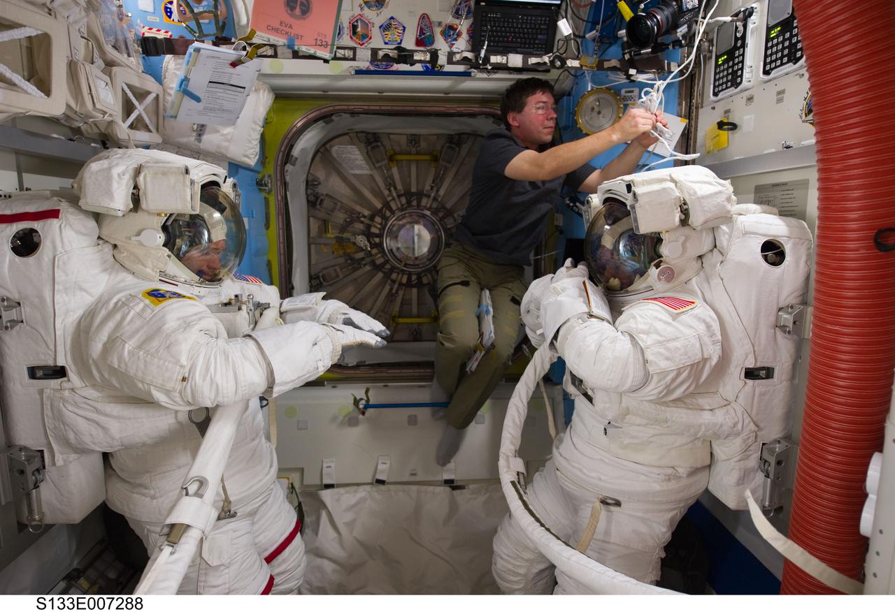S133-E-007288 (28 Feb. 2011) --- NASA astronauts Steve Bowen (left), Michael Barratt (center) and Alvin Drew, all STS-133 mission specialists, are pictured in the Quest airlock of the International Space Station as they prepare for the start of the mission's first spacewalk. Bowen and Drew are wearing Extravehicular Mobility Unit (EMU) spacesuits. Photo credit: NASA or National Aeronautics and Space Administration