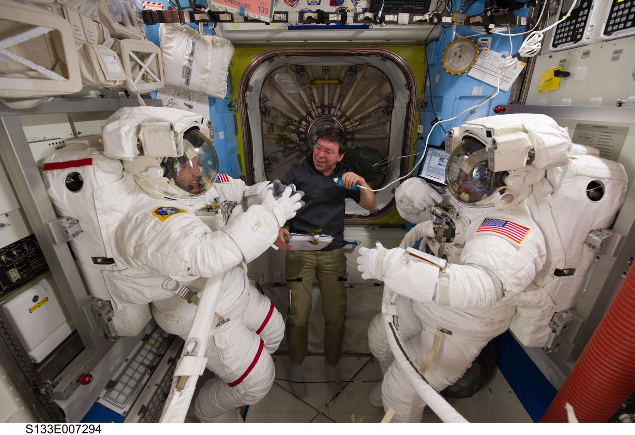 S133-E-007294 (28 Feb. 2011) --- NASA astronauts Steve Bowen (left), Michael Barratt (center) and Alvin Drew, all STS-133 mission specialists, are pictured in the Quest airlock of the International Space Station as they prepare for the start of the mission's first spacewalk. Bowen and Drew are wearing Extravehicular Mobility Unit (EMU) spacesuits. Photo credit: NASA or National Aeronautics and Space Administration