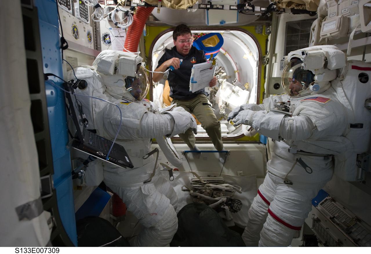 S133-E-007309 (28 Feb. 2011) --- NASA astronauts Steve Bowen (left), Michael Barratt (center) and Alvin Drew, all STS-133 mission specialists, are pictured in the Quest airlock of the International Space Station as they prepare for the start of the mission's first spacewalk. Bowen and Drew are wearing Extravehicular Mobility Unit (EMU) spacesuits. Photo credit: NASA or National Aeronautics and Space Administration