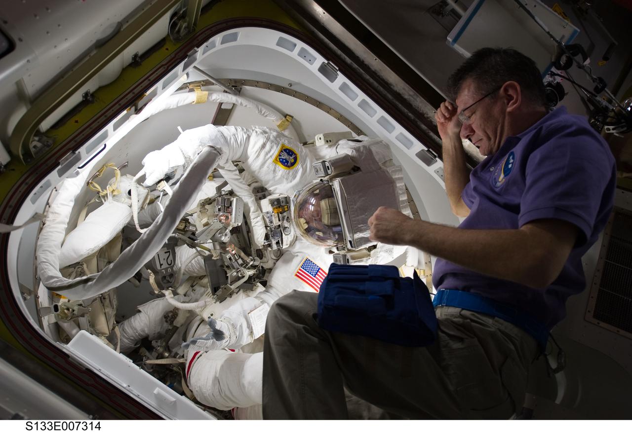 S133-E-007314 (28 Feb. 2011) --- Attired in their Extravehicular Mobility Unit (EMU) spacesuits, NASA astronauts Alvin Drew and Steve Bowen, both STS-133 mission specialists, prepare to exit the International Space Station?s Quest airlock to begin the mission?s first spacewalk. European Space Agency astronaut Paolo Nespoli (right), Expedition 26 flight engineer, assisted Drew and Bowen. Photo credit: NASA or National Aeronautics and Space Administration