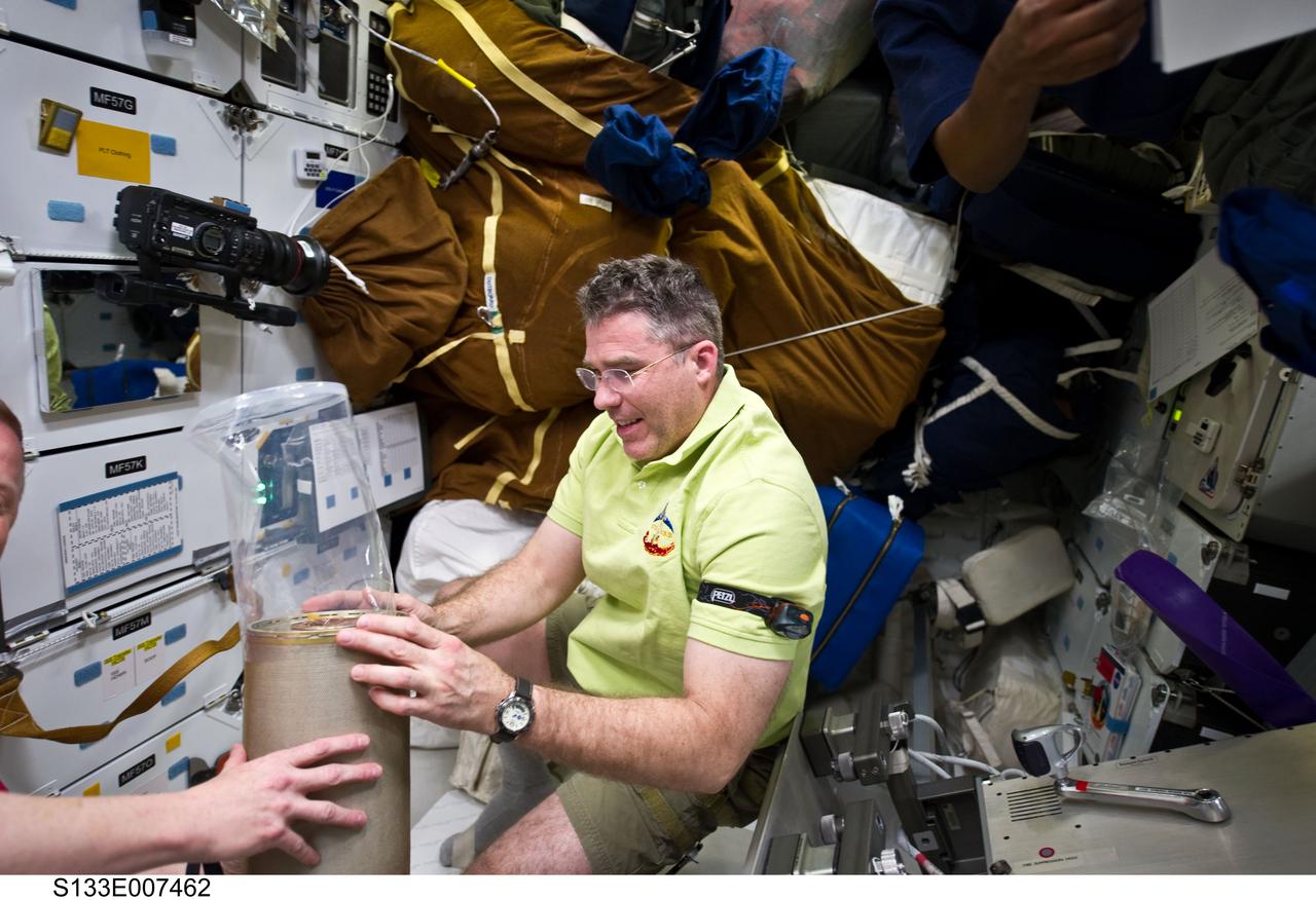 S133-E-007462 (28 Feb. 2011) --- NASA astronaut Steve Bowen, STS-133 mission specialist, works with lithium hydroxide (LiOH) canisters from beneath space shuttle Discovery’s middeck while docked with the International Space Station. Photo credit: NASA or National Aeronautics and Space Administration