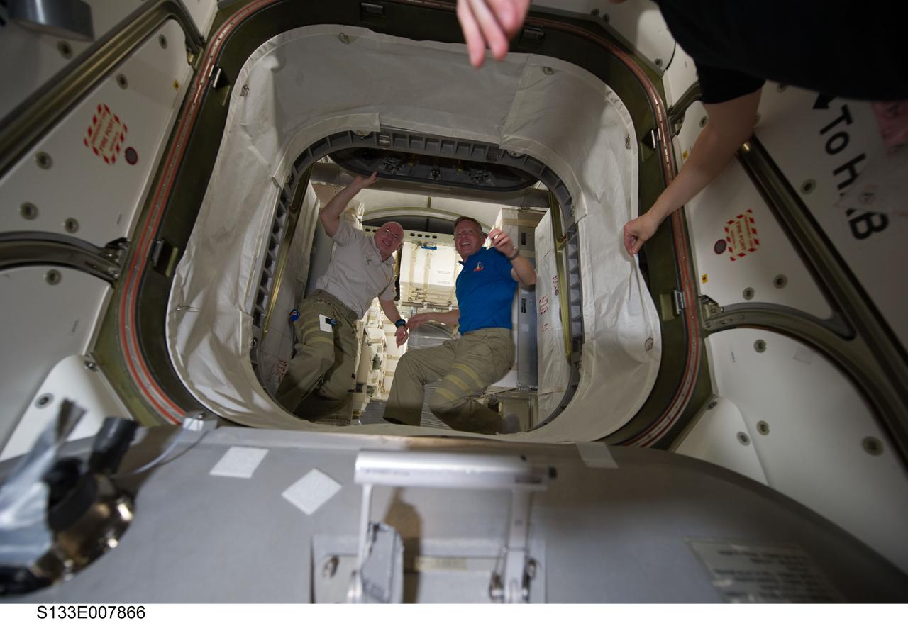 S133-E-007866 (1 March 2011) --- NASA astronauts Scott Kelly (left), Expedition 26 commander; and Steve Lindsey, STS-133 commander, are pictured in the hatch that leads to the newly-installed Permanent Multipurpose Module (PMM) of the International Space Station while space shuttle Discovery remains docked with the station. Photo credit: NASA or National Aeronautics and Space Administration
