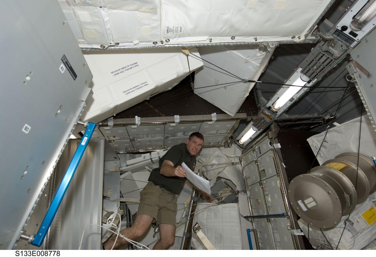 S133-E-008778 (5 March 2011) --- NASA astronaut Steve Bowen, STS-133 mission specialist, works in the Permanent Multipurpose Module (PMM) of the International Space Station while space shuttle Discovery remains docked with the station. Photo credit: NASA or National Aeronautics and Space Administration