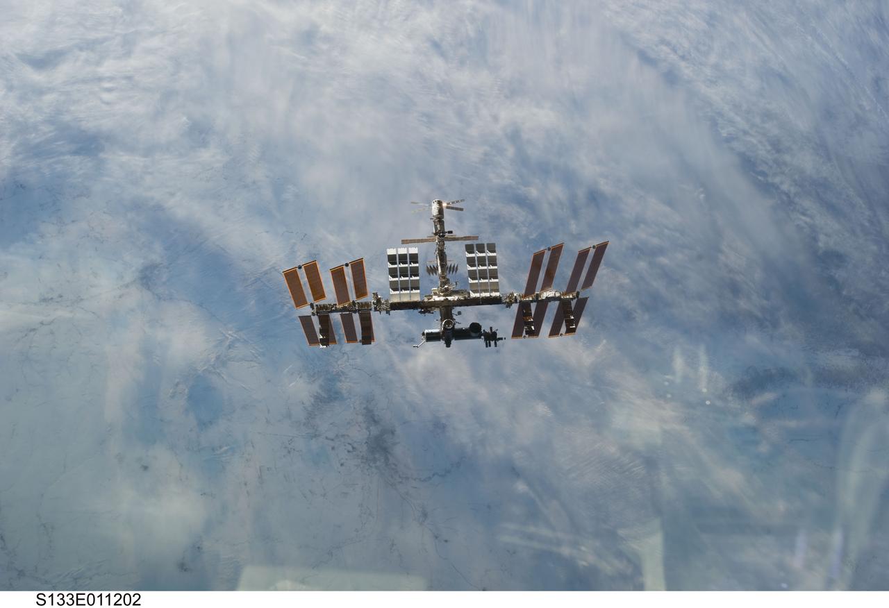S133-E-011202 (7 March 2011) ---  Backdropped against clouds over Earth, the International Space Station is seen from Discovery as the two orbital spacecraft accomplish their relative separation on March 7 after an aggregate of 12 astronauts and cosmonauts worked together for over a week. During a post undocking fly-around, the crew members aboard the two spacecraft collected a series of photos of each other’s vehicle. Photo credit: NASA or National Aeronautics and Space Administration