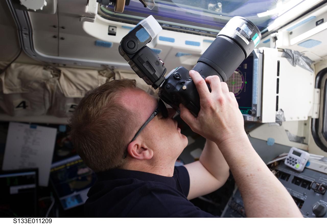 S133-E-011209 (7 March 2011) --- NASA astronaut Eric Boe, STS-133 pilot, uses a still camera at an overhead window on the aft flight deck of space shuttle Discovery during flight day 12 activities. Photo credit: NASA or National Aeronautics and Space Administration