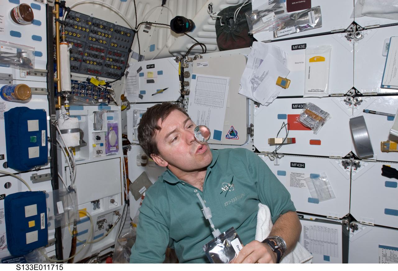 S133-E-011715 (7 March 2011) --- NASA astronaut Michael Barratt, STS-133 mission specialist, watches a water bubble float freely near him on the middeck of space shuttle Discovery during flight day 12 activities. Photo credit: NASA or National Aeronautics and Space Administration